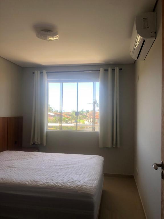a bedroom with a bed and a large window at Apartamento encantador in Itapoa