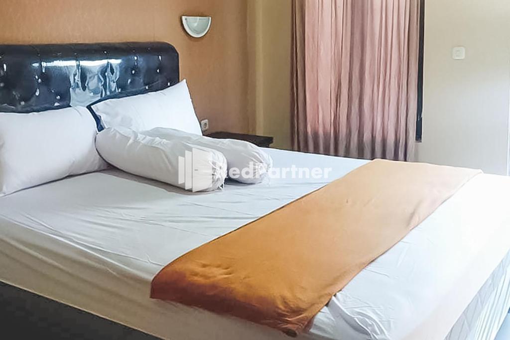 un letto con lenzuola e cuscini bianchi di Ardico Residence Syariah Mitra RedDoorz a Poponcal 2