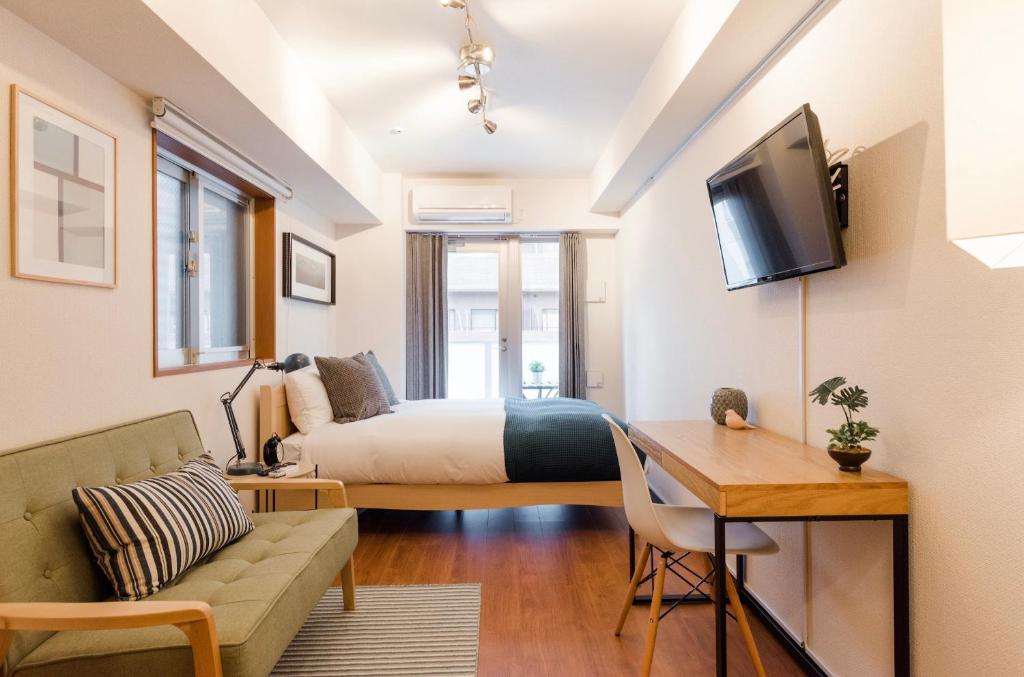 Habitación con cama, sofá y TV. en Dash Living Shinjuku, en Tokio