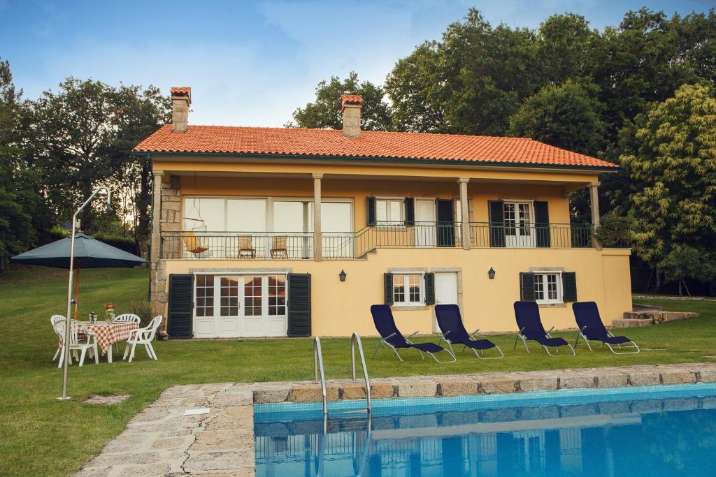 une maison avec des chaises et une piscine en face de celle-ci dans l'établissement Quinta das Marinhas de Paredes de Coura, à Paredes de Coura