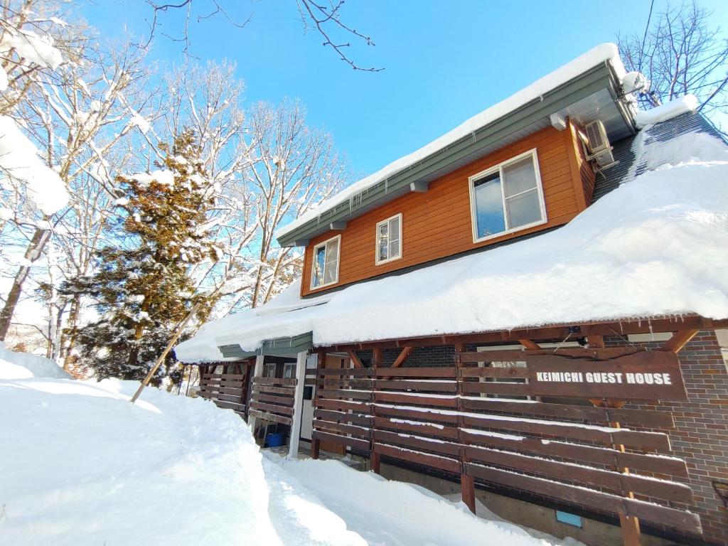 eine Blockhütte mit Schnee auf dem Dach in der Unterkunft Keimichi Guest House in Hakuba