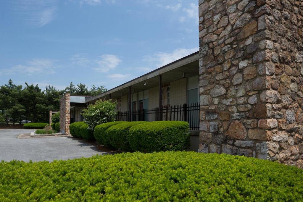 um edifício com arbustos verdes à sua frente em Luray Caverns Motels em Luray