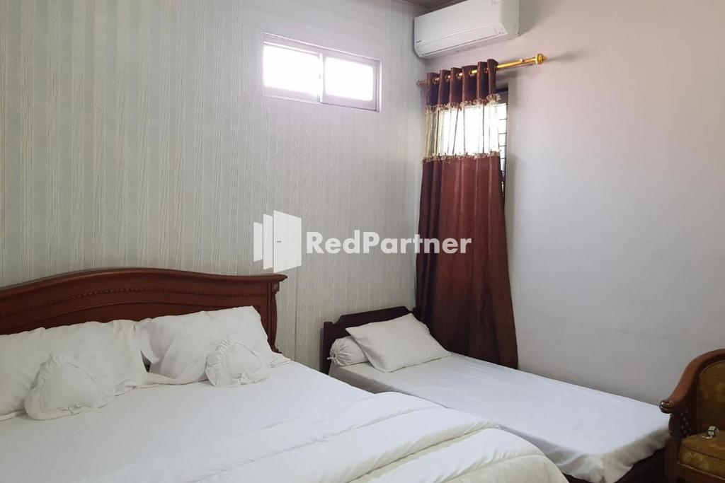 a bedroom with two beds and a window at Homestay Lotus Bangka Mitra RedDoorz in Pangkal Pinang