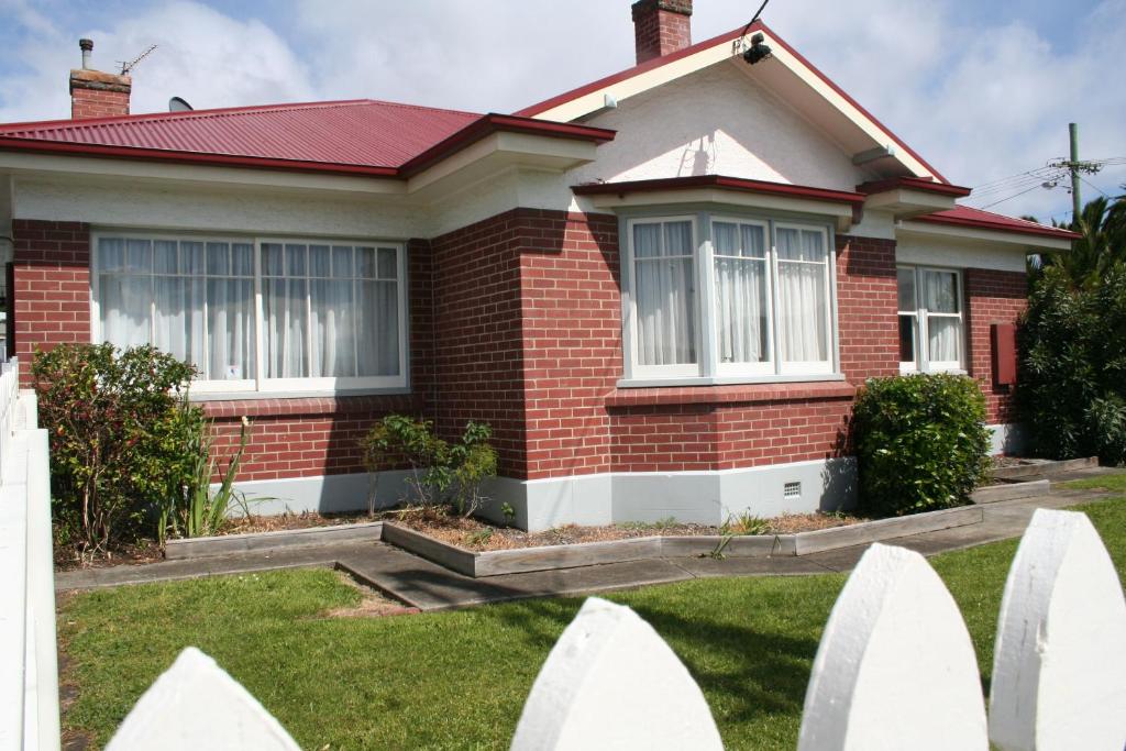 a house with a white picket fence in front of it at Moonah Central Apartments in Hobart