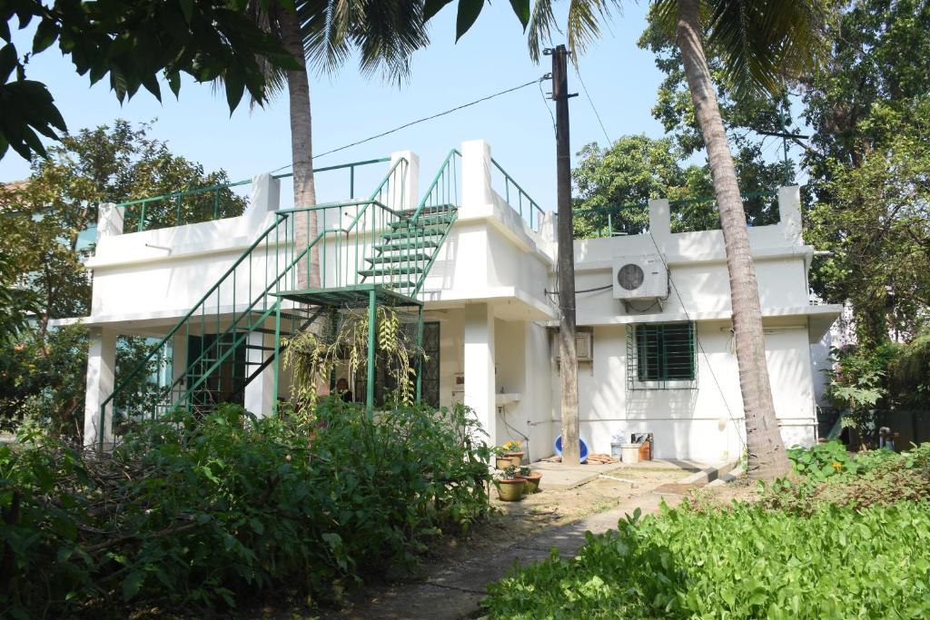 una casa blanca con una escalera delante en Bhitey Homestay SIMANTAPALLY / SHANTINIKETAN, en Santiniketan