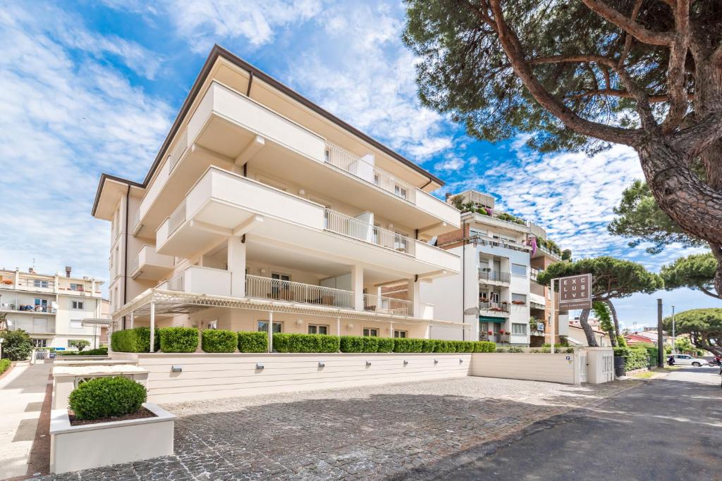 ein großes weißes Gebäude mit einem Baum davor in der Unterkunft Hotel & Residence Exclusive in Marina di Carrara