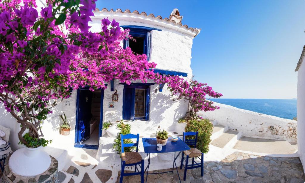 a white house with purple flowers and a table and chairs at Villea Seaview Apartments in Skopelos Town