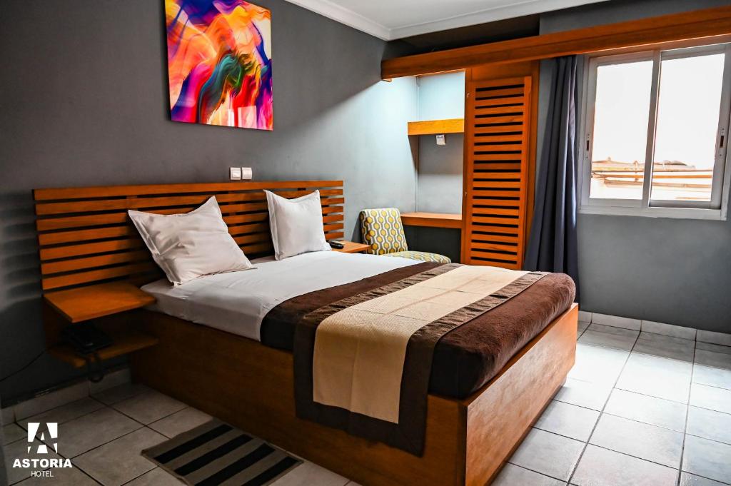 Un dormitorio con una cama grande y una ventana en Hotel Astoria, en Douala