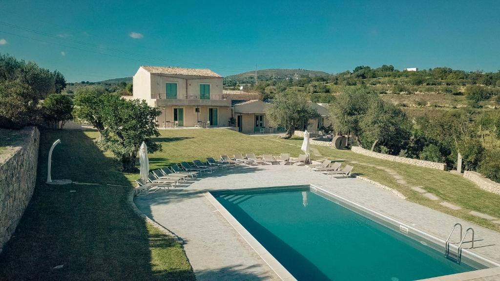 a large white swimming pool in front of a house at Relais Terre di Romanello in Noto