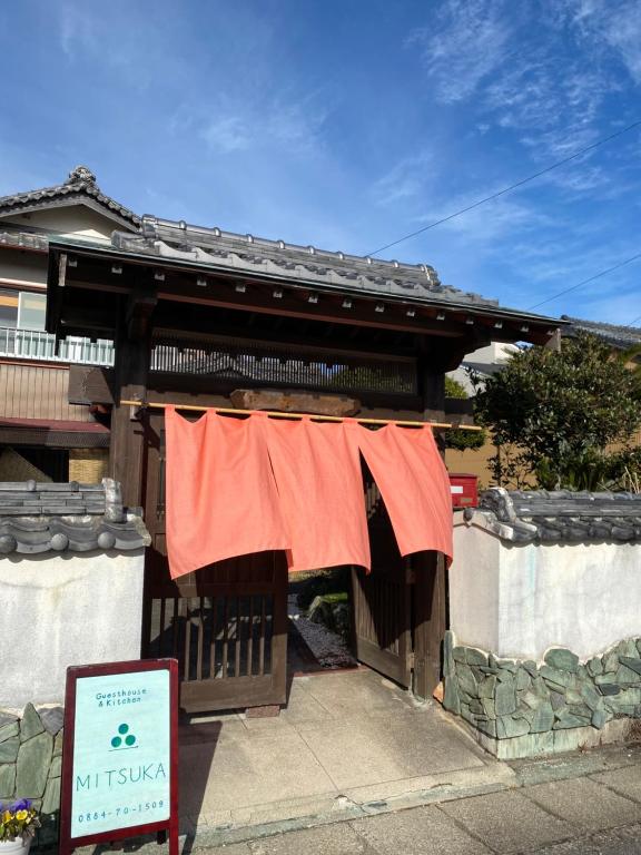 a house with a red shirt hanging from a gate at Guest House Mitsuka in Shishikui