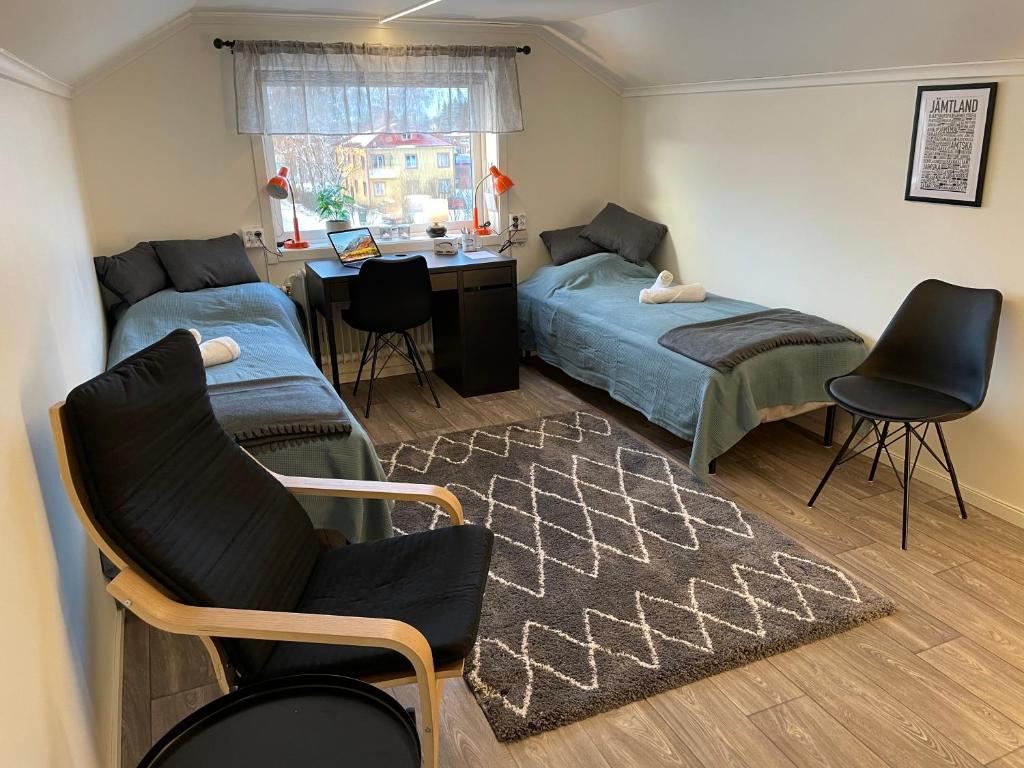 1 dormitorio con 2 camas, escritorio y silla en Vindsvåning centralt i Strömsund, en Strömsund