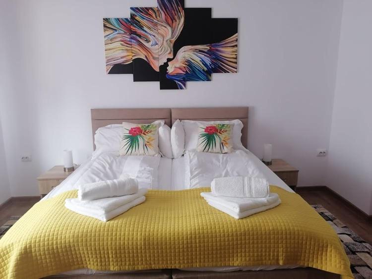 ein Schlafzimmer mit einem gelben Bett mit Handtüchern darauf in der Unterkunft Happy House in Hunedoara