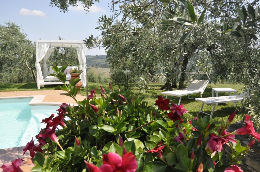 ein Pool mit zwei Stühlen und Blumen daneben in der Unterkunft Tognazzi Casa Vacanze - Villa San Martino in Villa del Monte