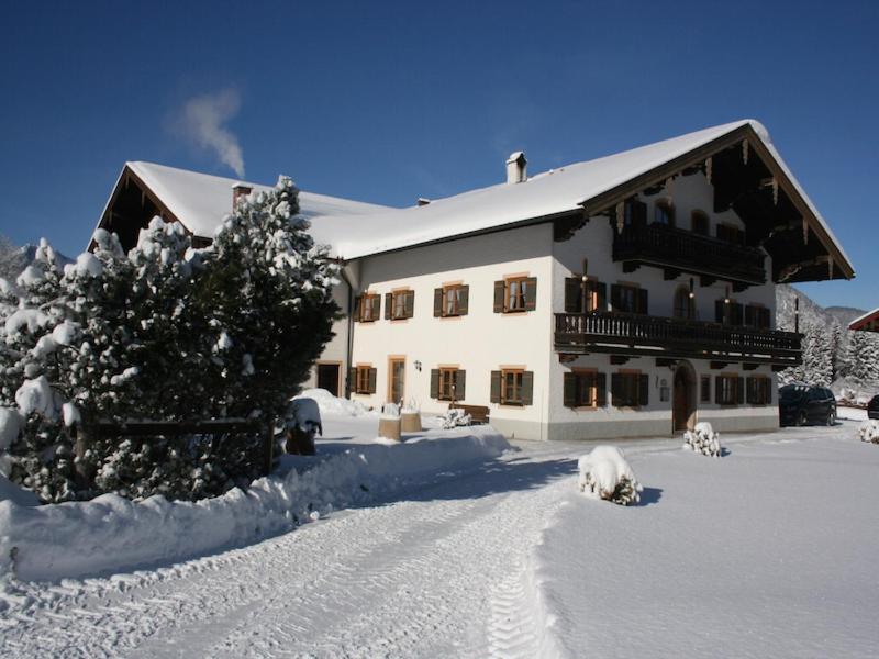 una casa cubierta de nieve con un árbol delante de ella en Ferienwohnungen Ortner-Hof, en Ruhpolding