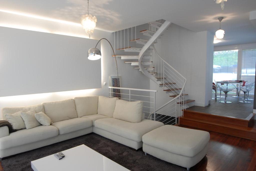 un soggiorno con divano bianco e scala a chiocciola di Go Donosti Villa Buda a San Sebastián