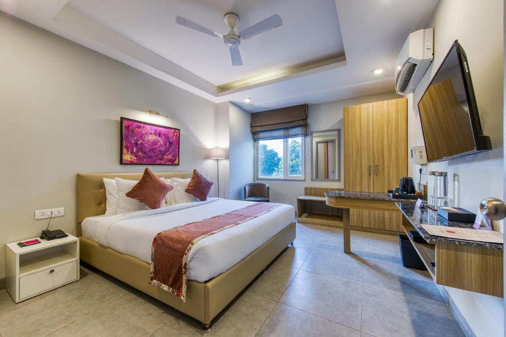 a hotel room with a bed and a desk at ROSASTAYS Gurugram Sec 31 in Gurgaon