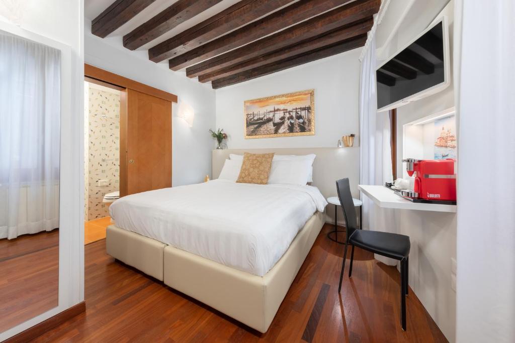una camera con un grande letto bianco e una scrivania di Spadaria San Marco Guest House a Venezia