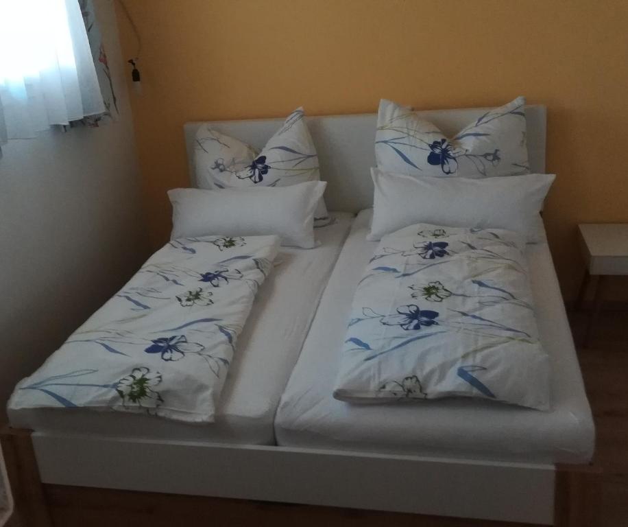 Una cama con almohadas blancas y flores azules. en Kellerstöckl Petra, en Eisenberg an der Pinka
