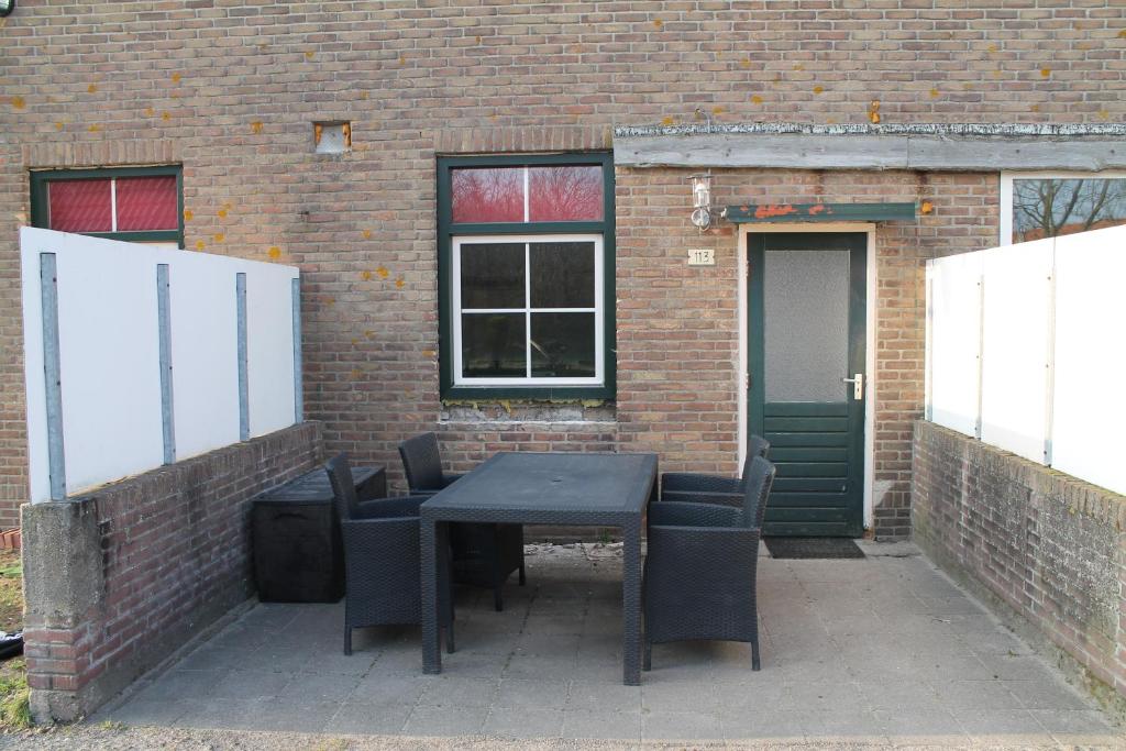 a black table and chairs in front of a brick building at boerderij de duinen 113 in De Cocksdorp