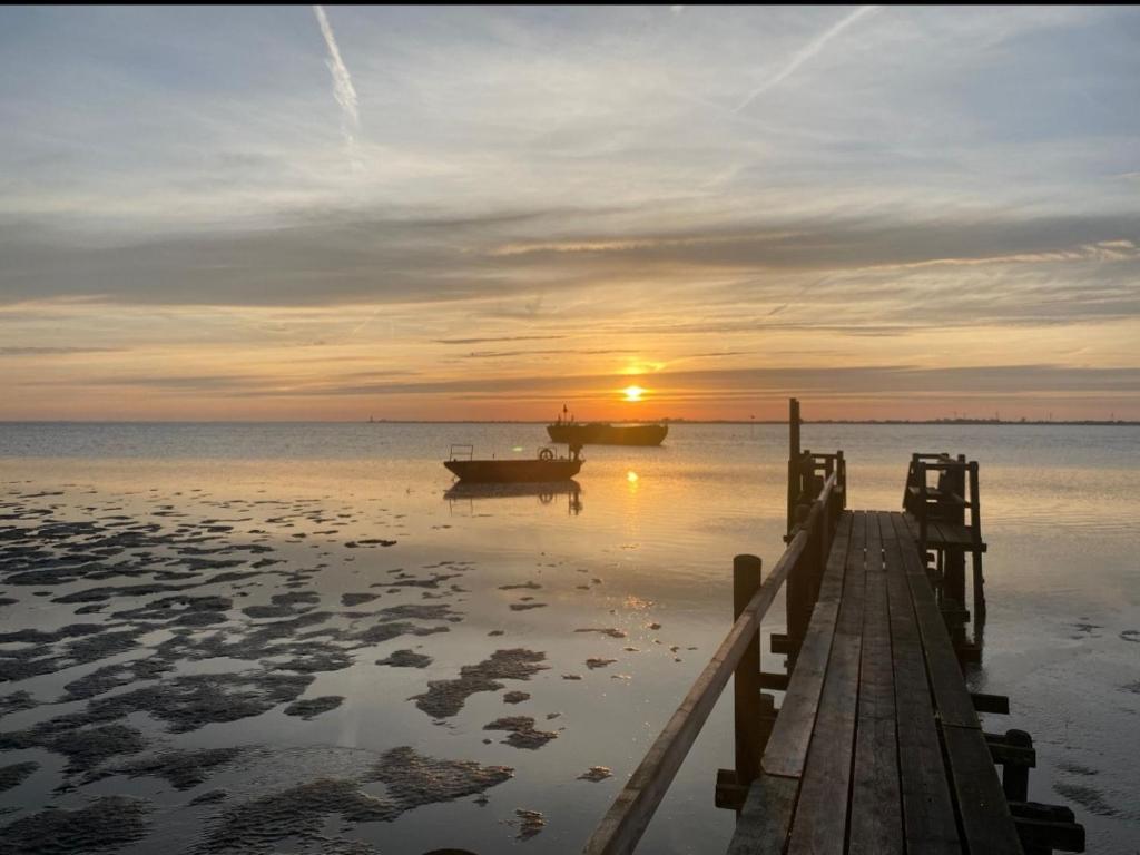 ein Dock mit zwei Booten im Wasser bei Sonnenuntergang in der Unterkunft Auszeit an der Nordsee in Husum