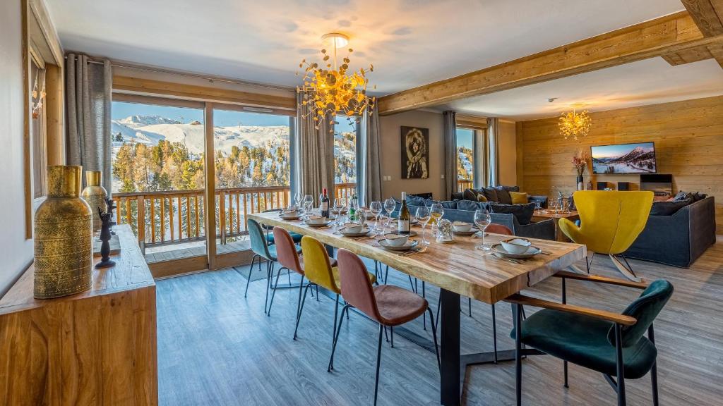 a dining room with a table and chairs and a couch at Chalet Hugo by Les Etincelles in Belle Plagne