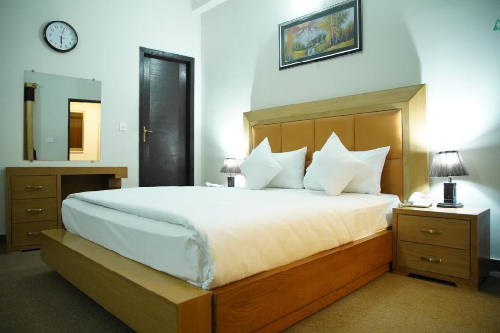 a bedroom with a large bed and a clock on the wall at Hotel Red Line in Islamabad