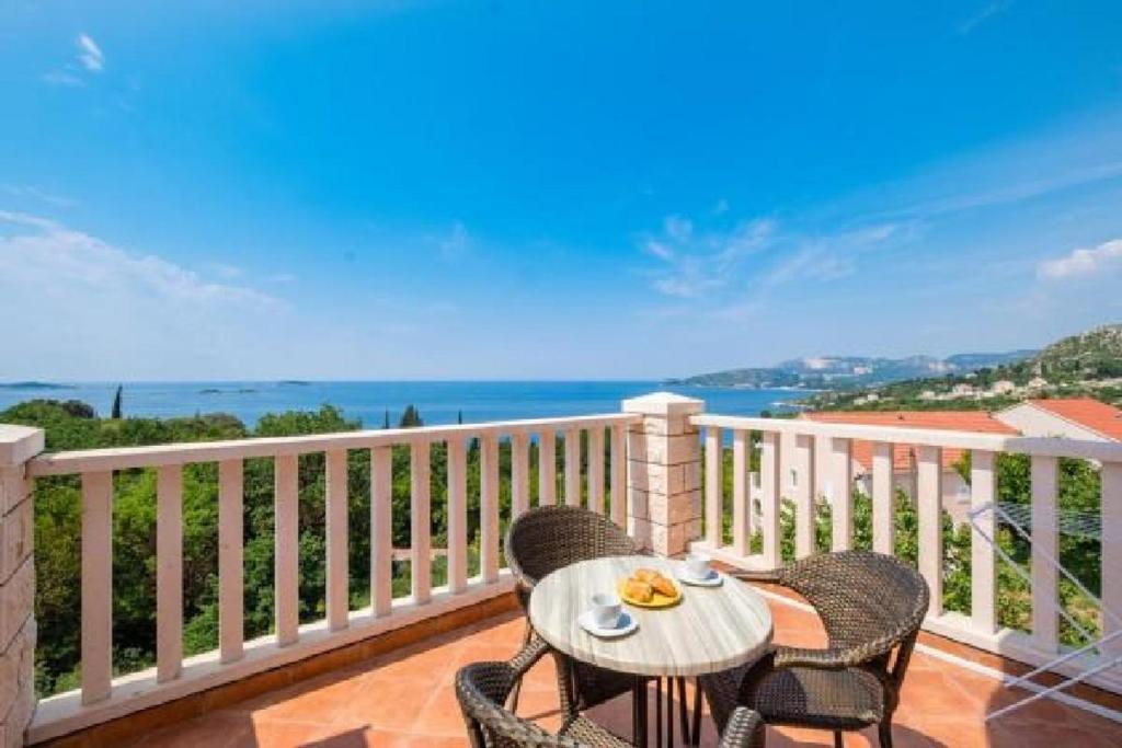 una mesa y sillas en un balcón con vistas al océano en Villa Panorama Dubrovnik, en Mlini