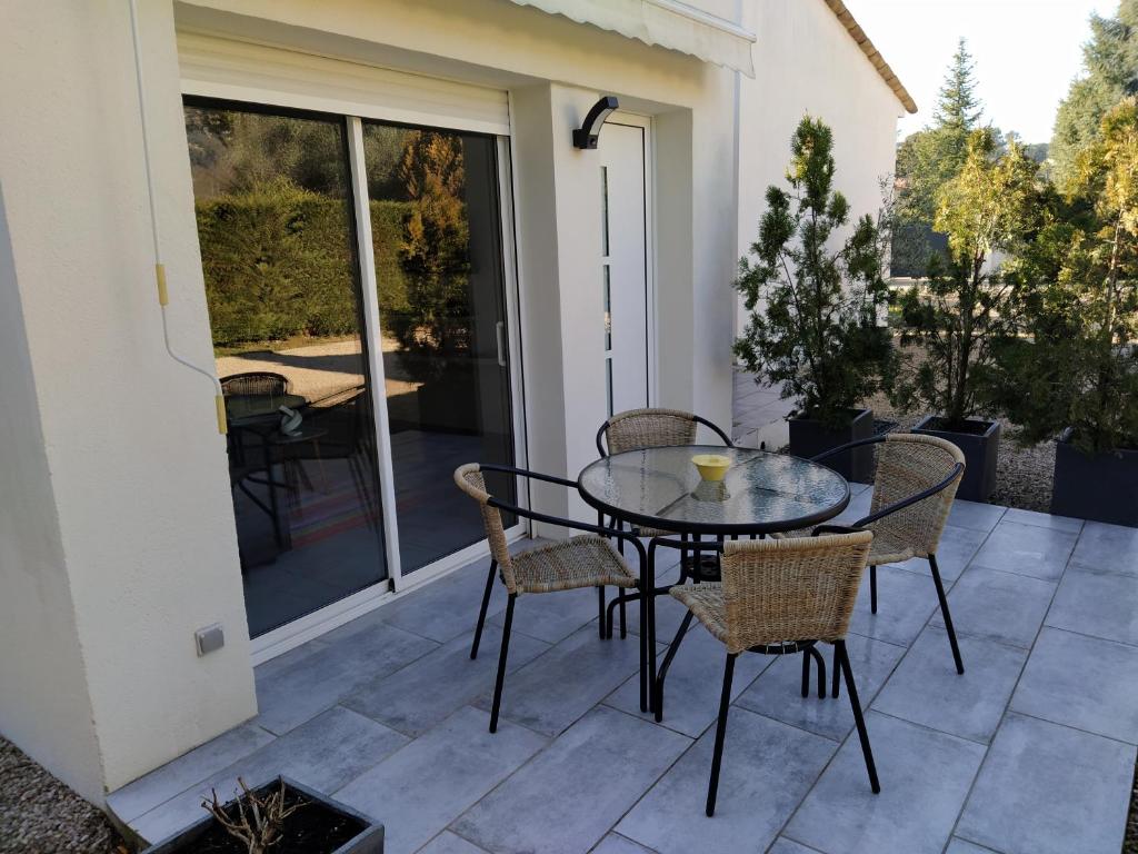 a glass table and chairs on a patio at la pinède in Peymeinade