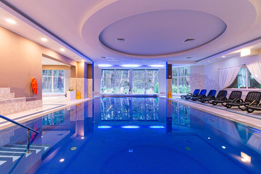 a large swimming pool in a hotel with chairs in it at Bagińscy Spa in Pobierowo