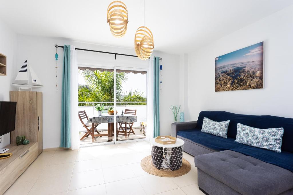 - un salon avec un canapé bleu et une table dans l'établissement Home2Book Stunning Apartment Bajamar, à Bajamar