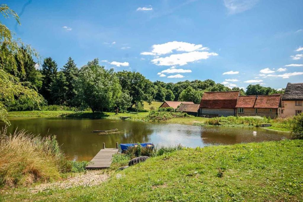 une rivière avec un quai en bois au milieu dans l'établissement Mill Cottage set beside a Mill pond in a 70 acre Nature Reserve Bliss, à Assington