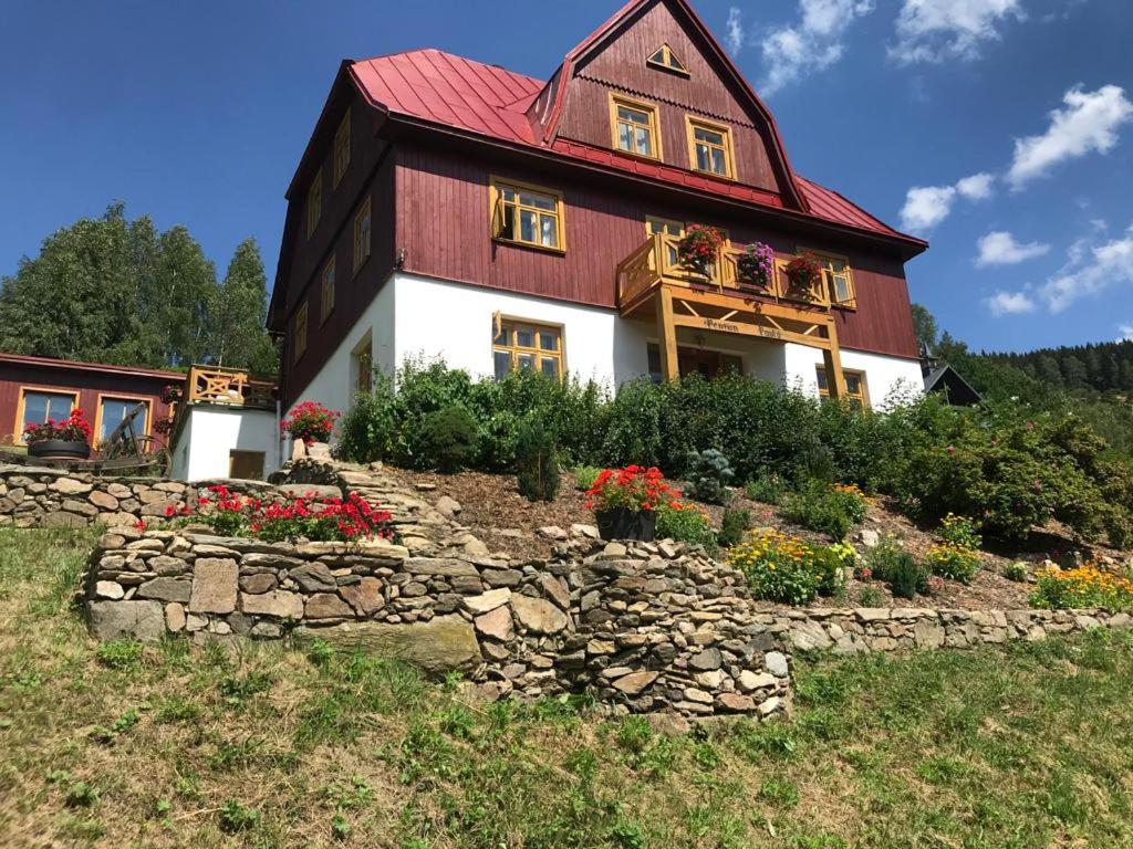 een huis met een rood dak en een stenen muur bij Pension Paulů in Pec pod Sněžkou