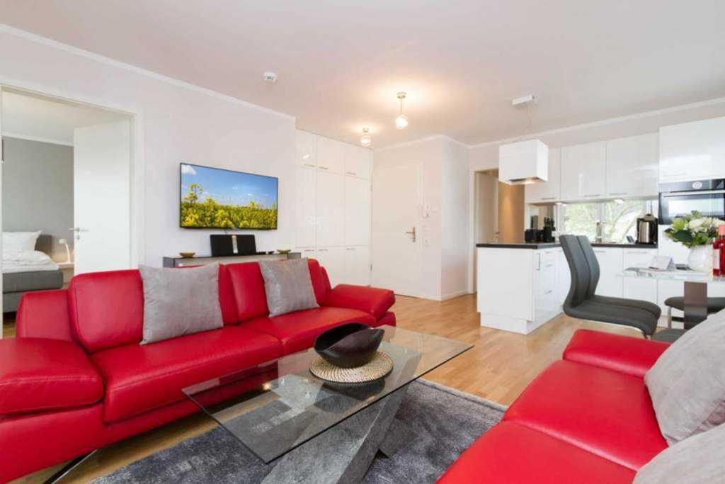 uma sala de estar com um sofá vermelho e uma cozinha em Duenenresidenz Heringsdorf App 18 em Bansin