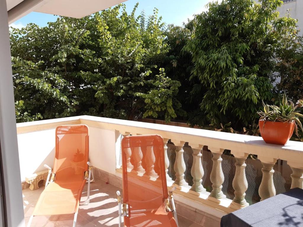 dwa krzesła na balkonie z drzewami w tle w obiekcie Perle de Gammarth w mieście Gammarth
