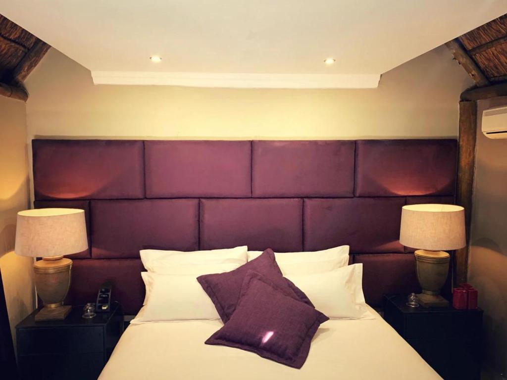 sypialnia z dużym łóżkiem z fioletowym zagłówkiem w obiekcie Little Eden Guest Lodge w mieście Vanderbijlpark