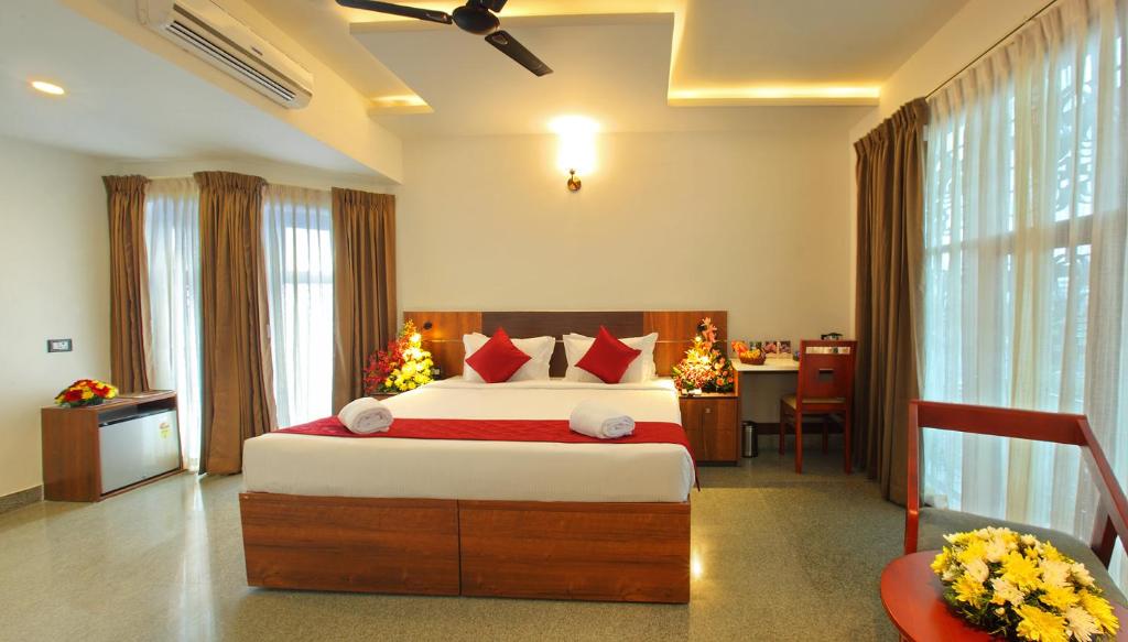 a bedroom with a large bed and a desk at Hotel Thamburu International in Trivandrum