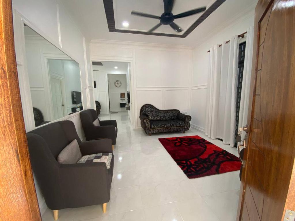 a living room with two couches and a ceiling fan at ADDA Guest House in Kota Bharu