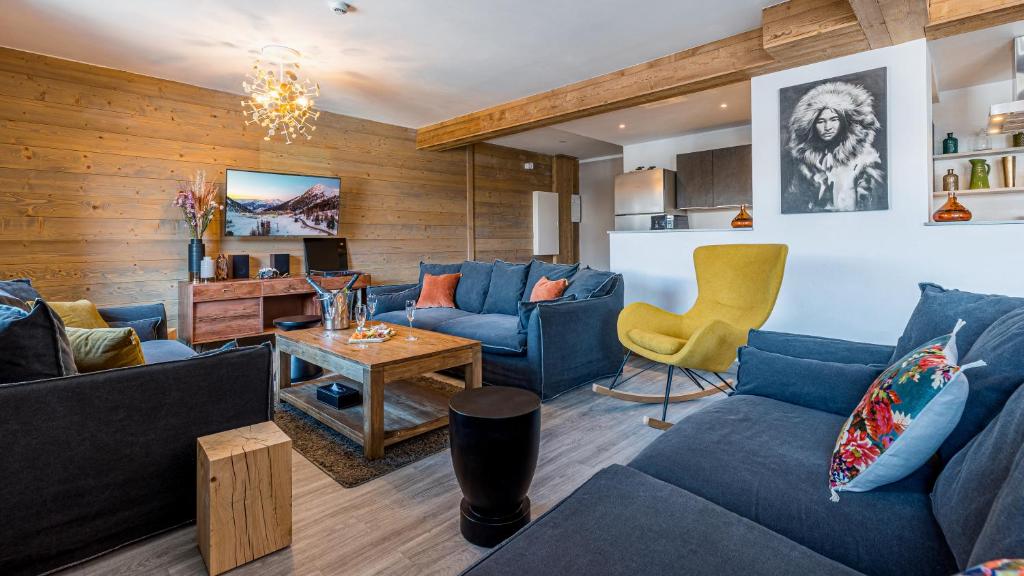 Una sala de estar con sofás azules y una mesa. en Chalet Violette by Les Etincelles, en La Plagne