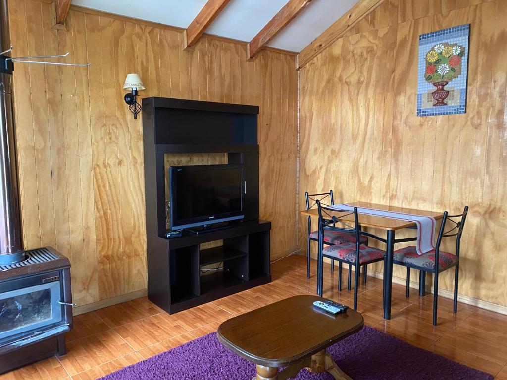 a living room with a table and a television at Cabaña Cris in Cochrane