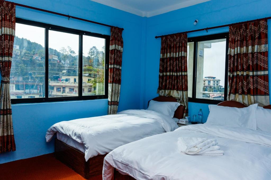 two beds in a blue room with two windows at Nagarkot Nayagaun Homestay in Nagarkot
