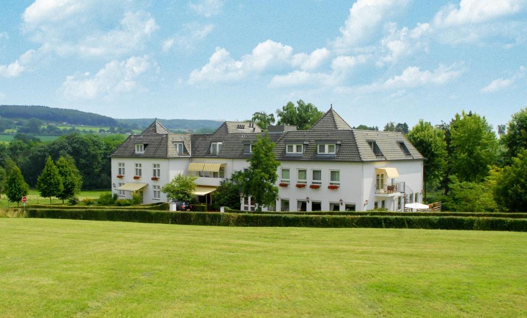 a large white house with a large grass field at Hotel Inkelshoes in Epen