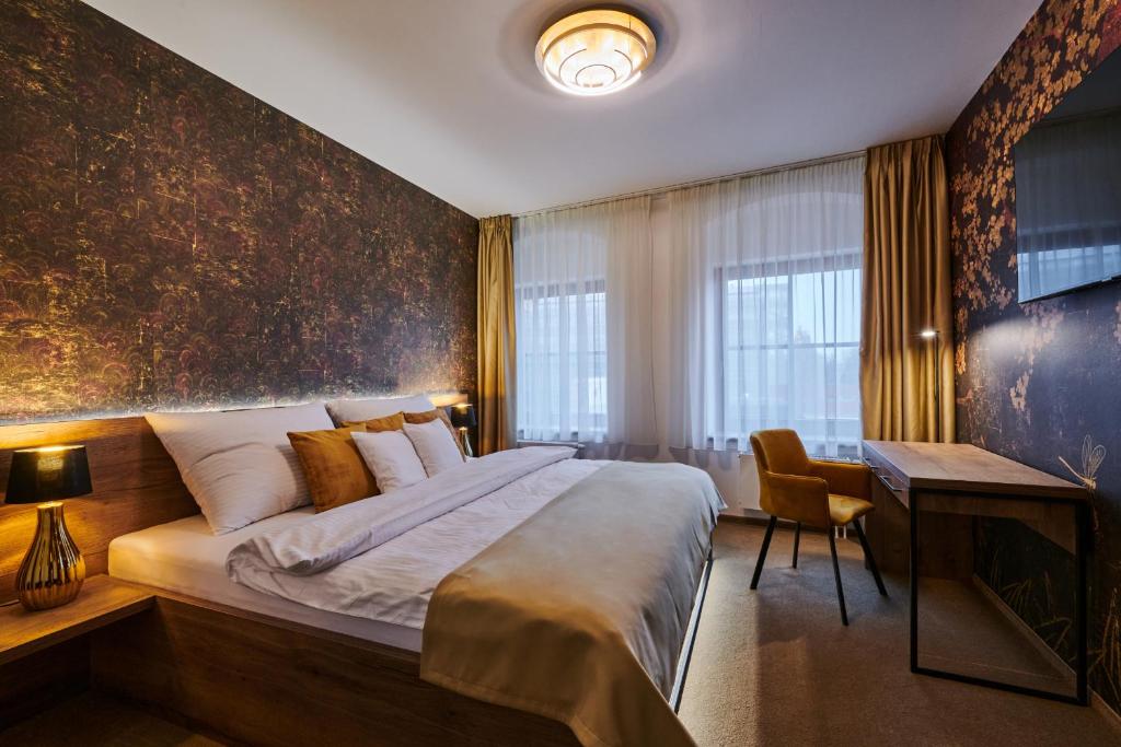 a bedroom with a large bed and a desk at Hotel Alfréd a Hermína in Olomouc