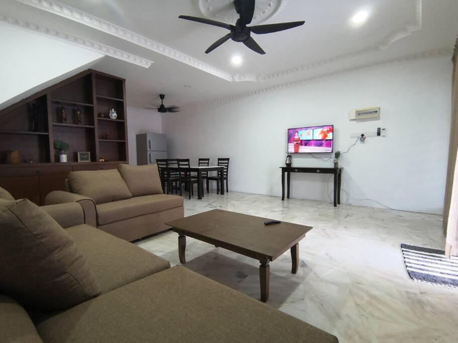 The Pigeon Alor Akar Guest House في كُوانتان: غرفة معيشة مع أريكة ومروحة سقف