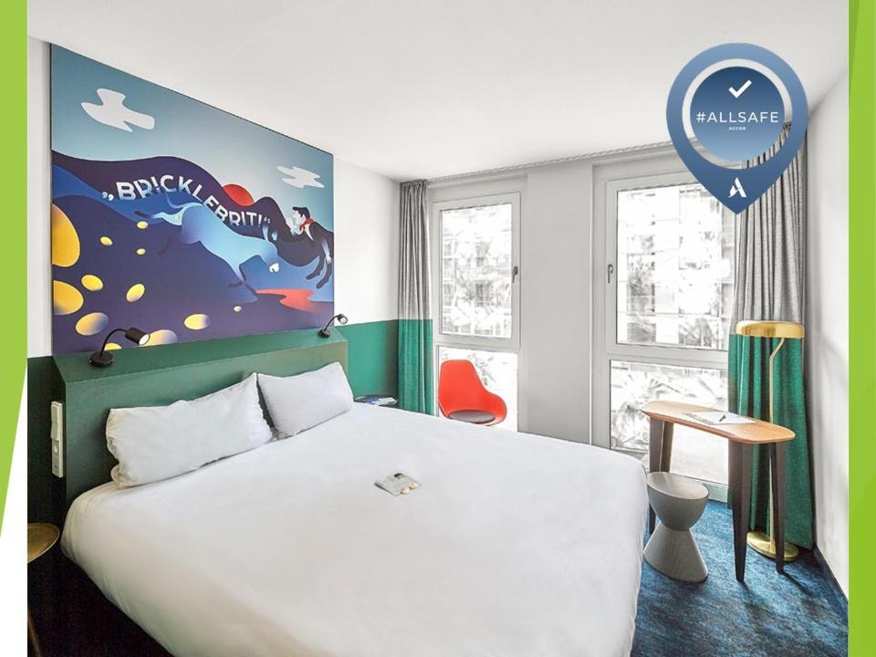 - une chambre avec un grand lit blanc et un panneau dans l'établissement ibis Styles Pforzheim, à Pforzheim