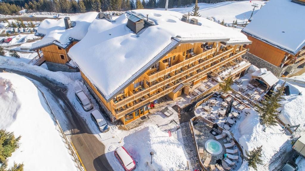 Un bâtiment avec de la neige au sommet dans la neige dans l'établissement Madame Vacances Hôtel & Spa Le Mottaret, à Méribel