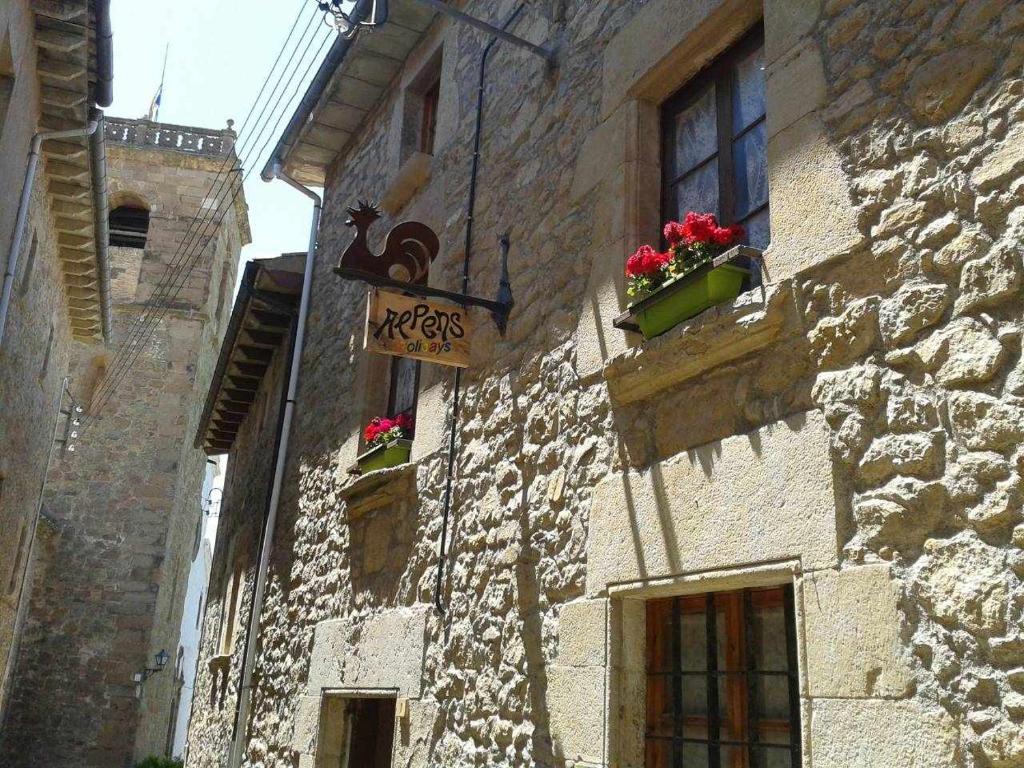 un edificio in pietra con dei fiori sul lato di Alpens Holidays Ca la Cèlia ad Alpens