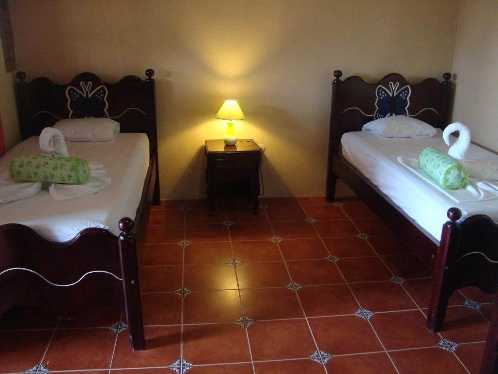 Habitación con 2 camas y mesa con lámpara. en Ecolodge Blue Morpho, en Cárdenas