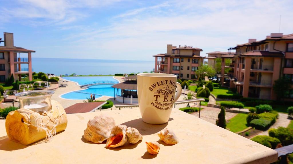 a cup of coffee sitting on a table next to some food at Луксозни Апартаменти Калиакрия - Luxurious Apartments in Kaliakria Resort in Topola