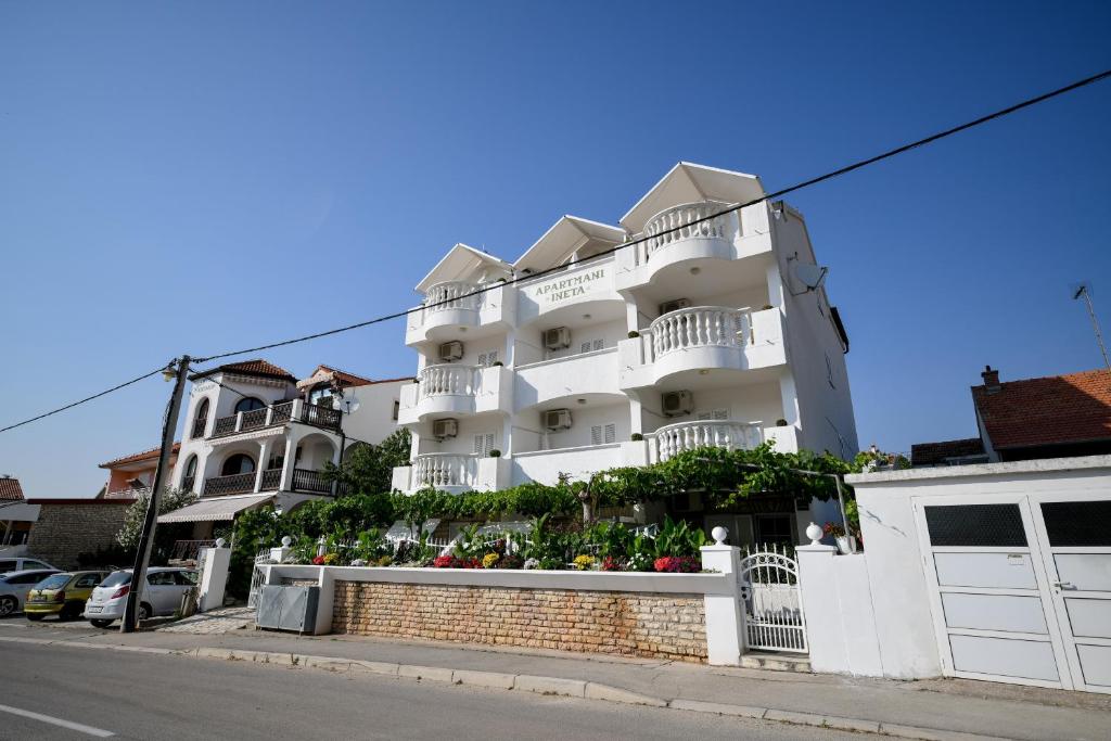 a white apartment building on the side of a street at Apartments Ineta in Sveti Filip i Jakov