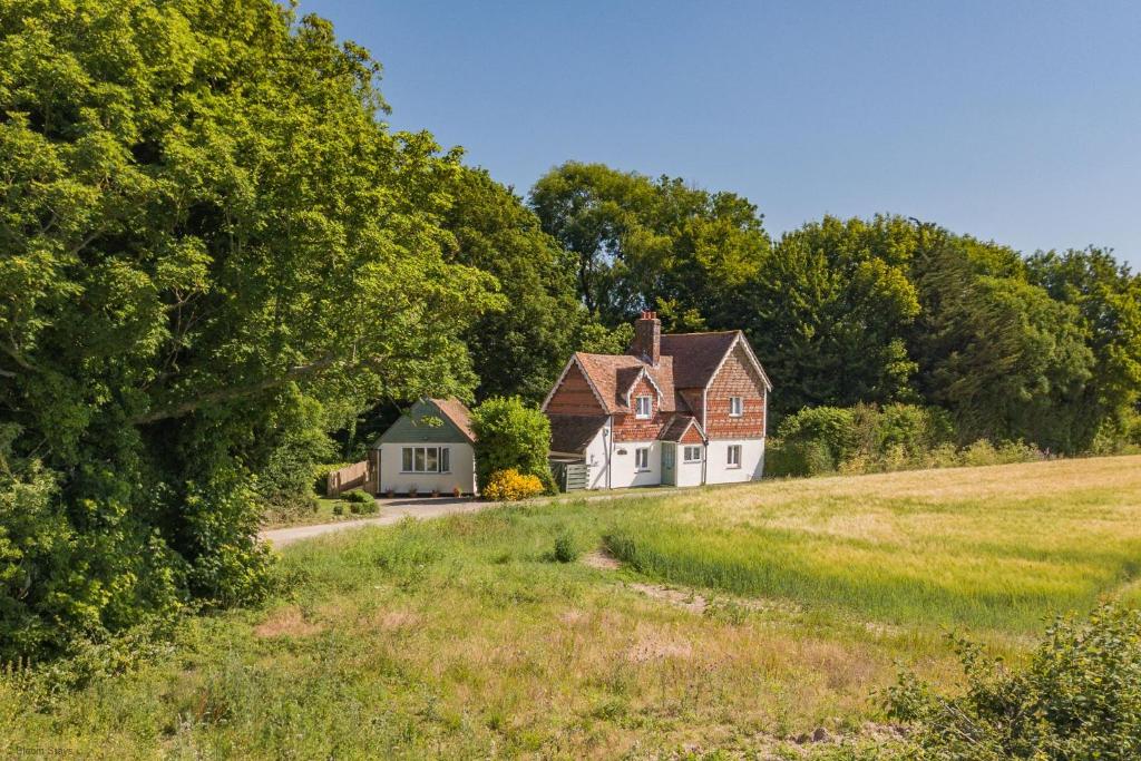 uma casa ao lado de um campo com árvores em Pheasants Lodge by Bloom Stays em Canterbury